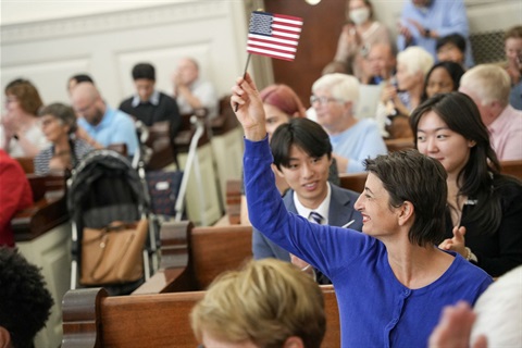 Woman holds up flag during Naturalization Ceremony in Tompkins County